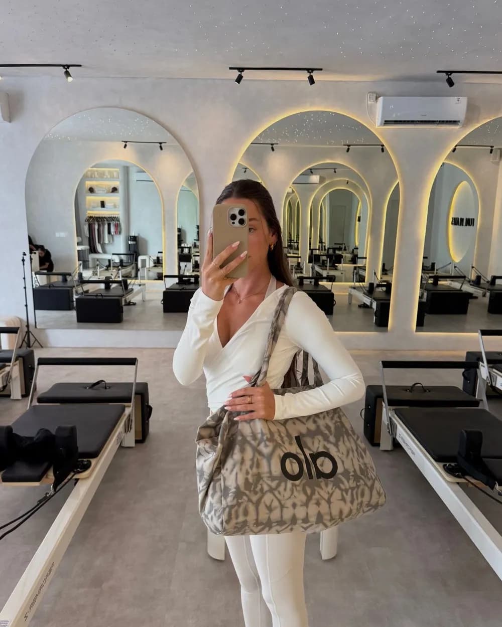 All white activewear with a printed tote in a pilates studio